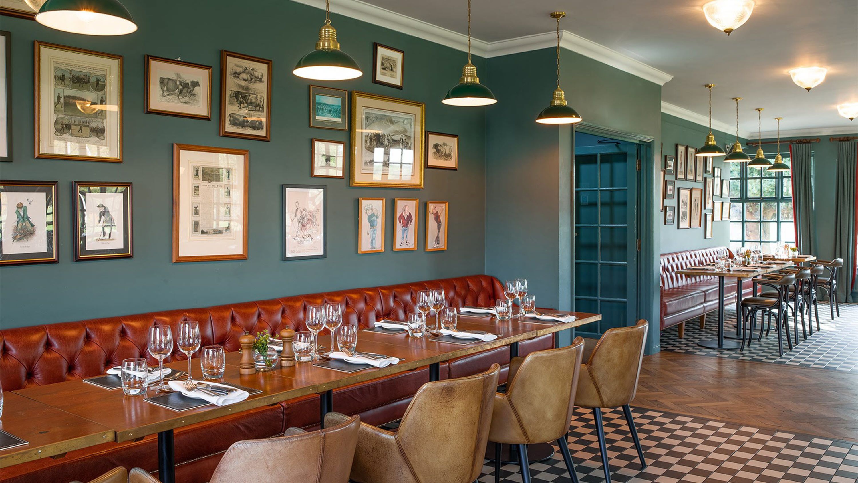 A restaurant with a long wooden bench seating area, framed pictures on the walls, and a checkered floor.