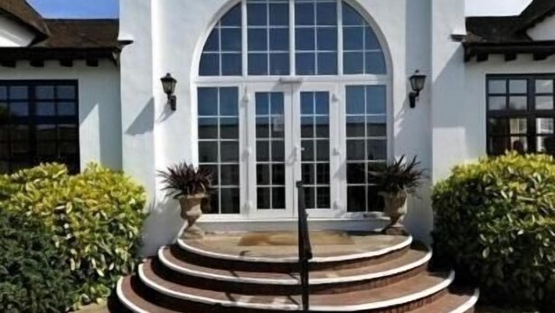 A white building with a large arched window and a set of steps leading to the entrance. - Thorpeness Golf Club and Hotel (Leiston)