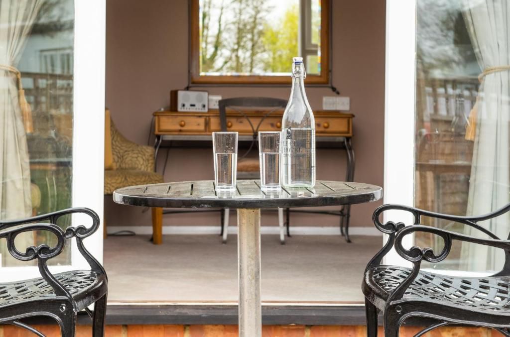 Une table ronde avec deux chaises, une bouteille et deux verres dessus.