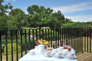 A table set outdoors with a view of a garden and trees. - Thorpeness Golf Club and Hotel (Leiston)