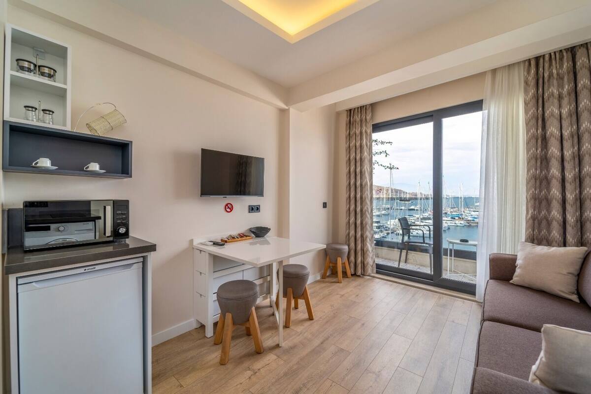 A modern apartment with a kitchen, dining area, and a large balcony with a marina view.