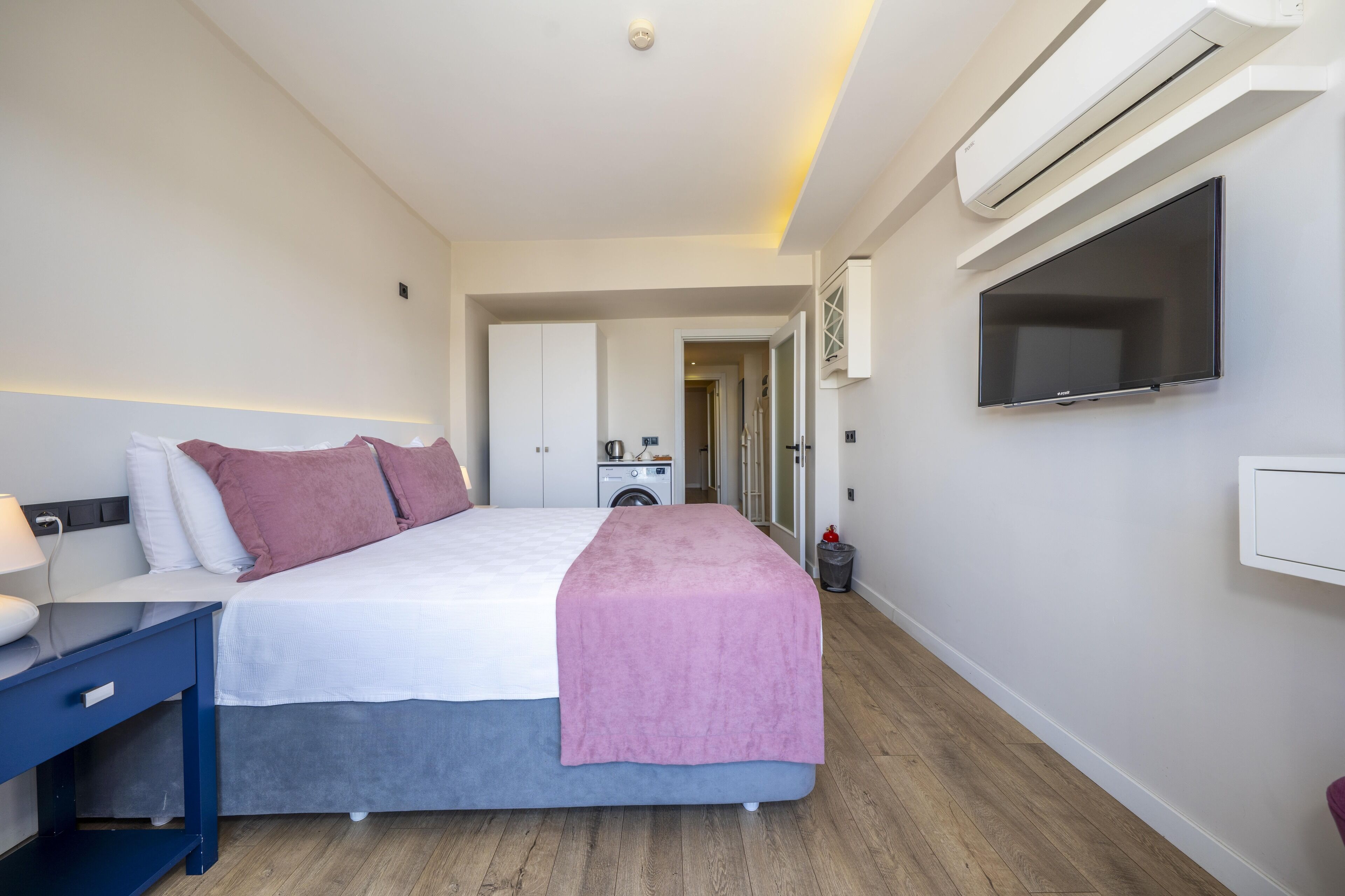 Ein modernes Hotelzimmer mit Bett, Schreibtisch, Flachbildfernseher und Klimaanlage.