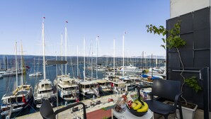 A balcony with a table, chairs, and a potted plant overlooking a marina with multiple sailboats. - Ece Marina Suites (Fethiye)