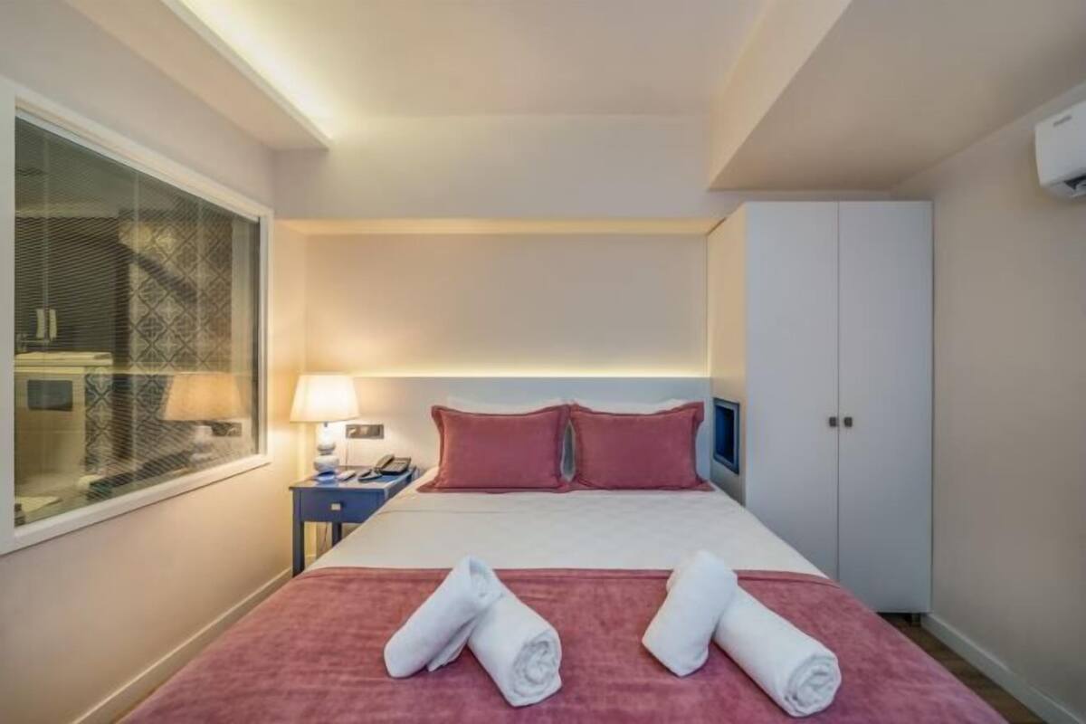 A hotel room with a bed, a nightstand, a lamp, a TV, and a wardrobe.