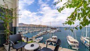 A balcony with two chairs and a table overlooking a marina with numerous boats docked. - Ece Marina Suites (Fethiye)