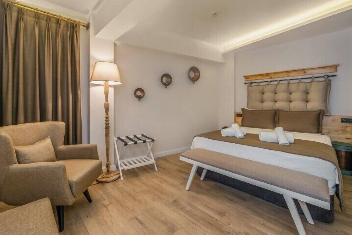 A hotel room with a bed, a chair, a lamp, and a coat rack.