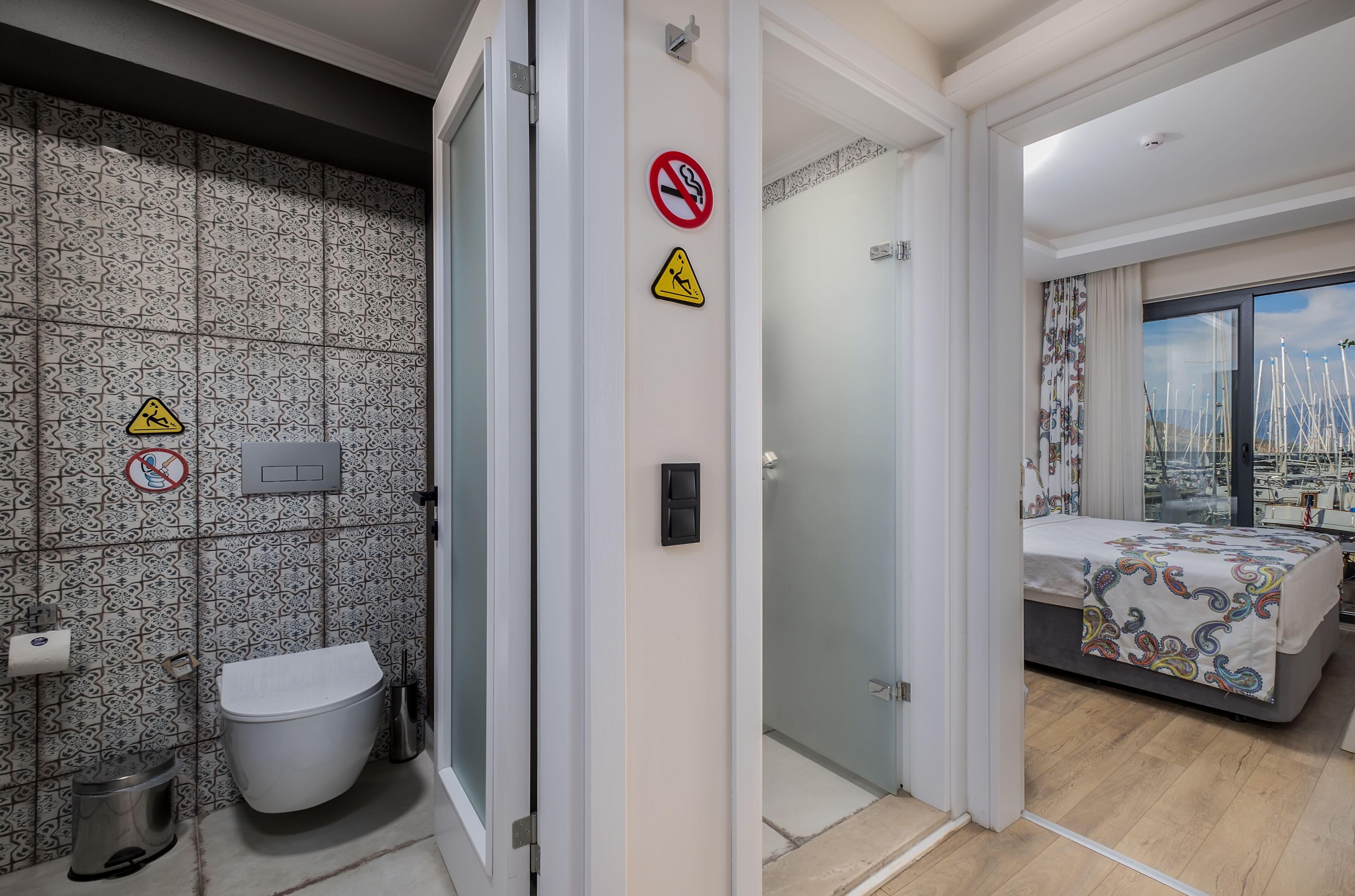 A modern bathroom with patterned tiles, a toilet, and a trash bin.