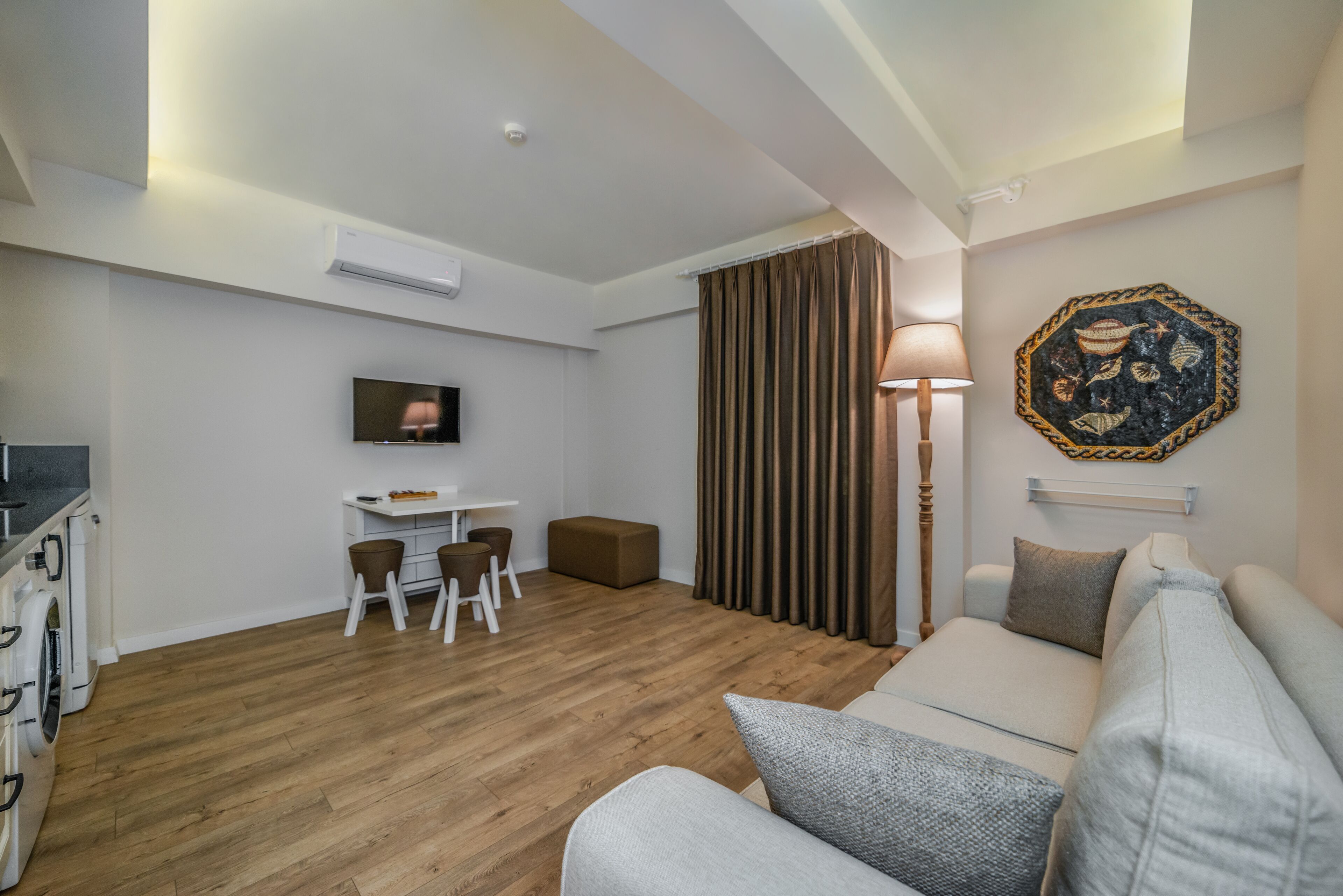 Ein modernes Wohnzimmer mit einer Couch, einem Essbereich mit Tisch und Stühlen, einem Fernseher und einem Wandbild.
