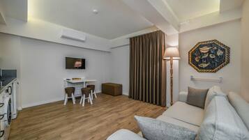 Ein modernes Wohnzimmer mit einer Couch, einem Essbereich mit Tisch und Stühlen, einem Fernseher und einem Wandbild.