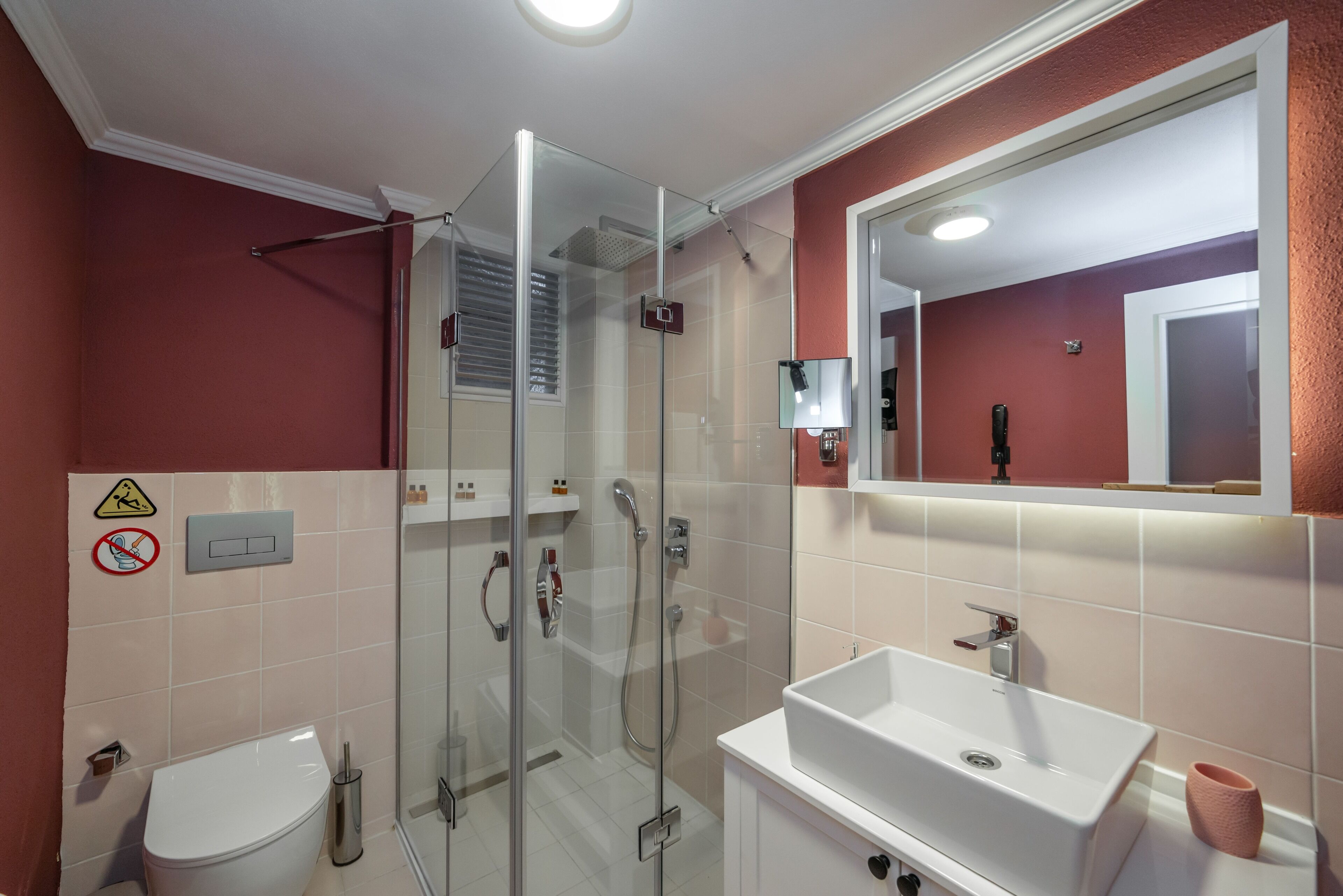 Ein modernes Badezimmer mit einer Duschkabine, einem weißen Waschbecken und einer Toilette.