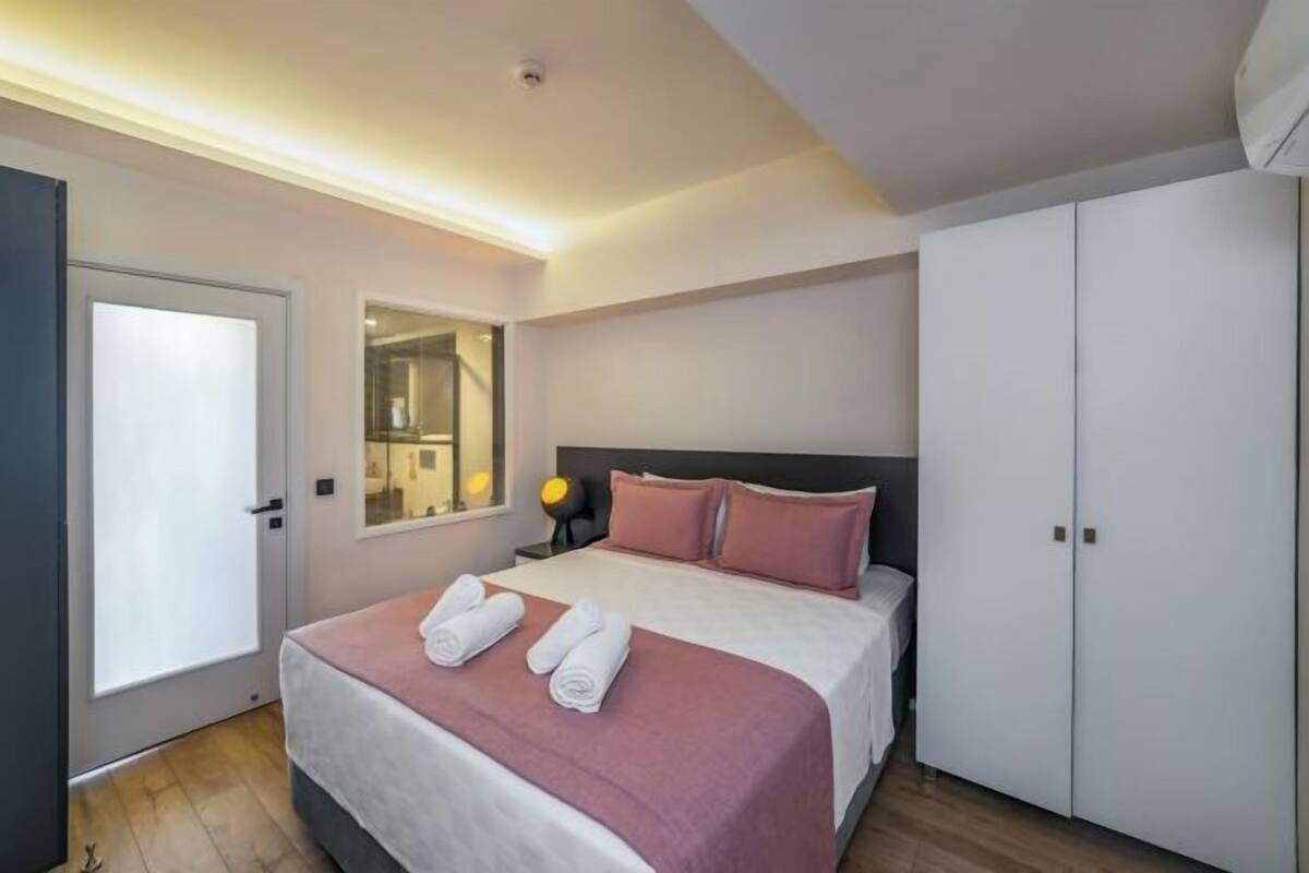 A modern bedroom with a bed, a wardrobe, a mirror, and a door.