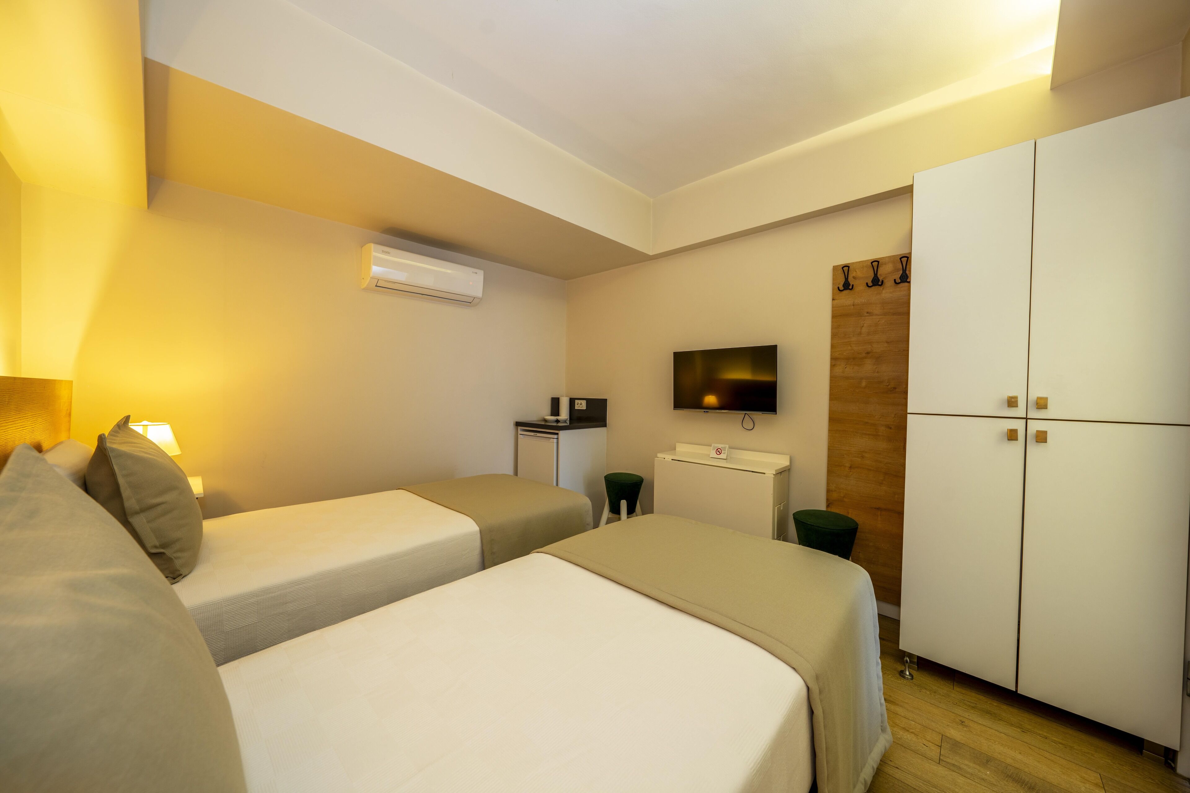 Une chambre d’hôtel avec deux lits, un bureau, une télévision et une armoire.