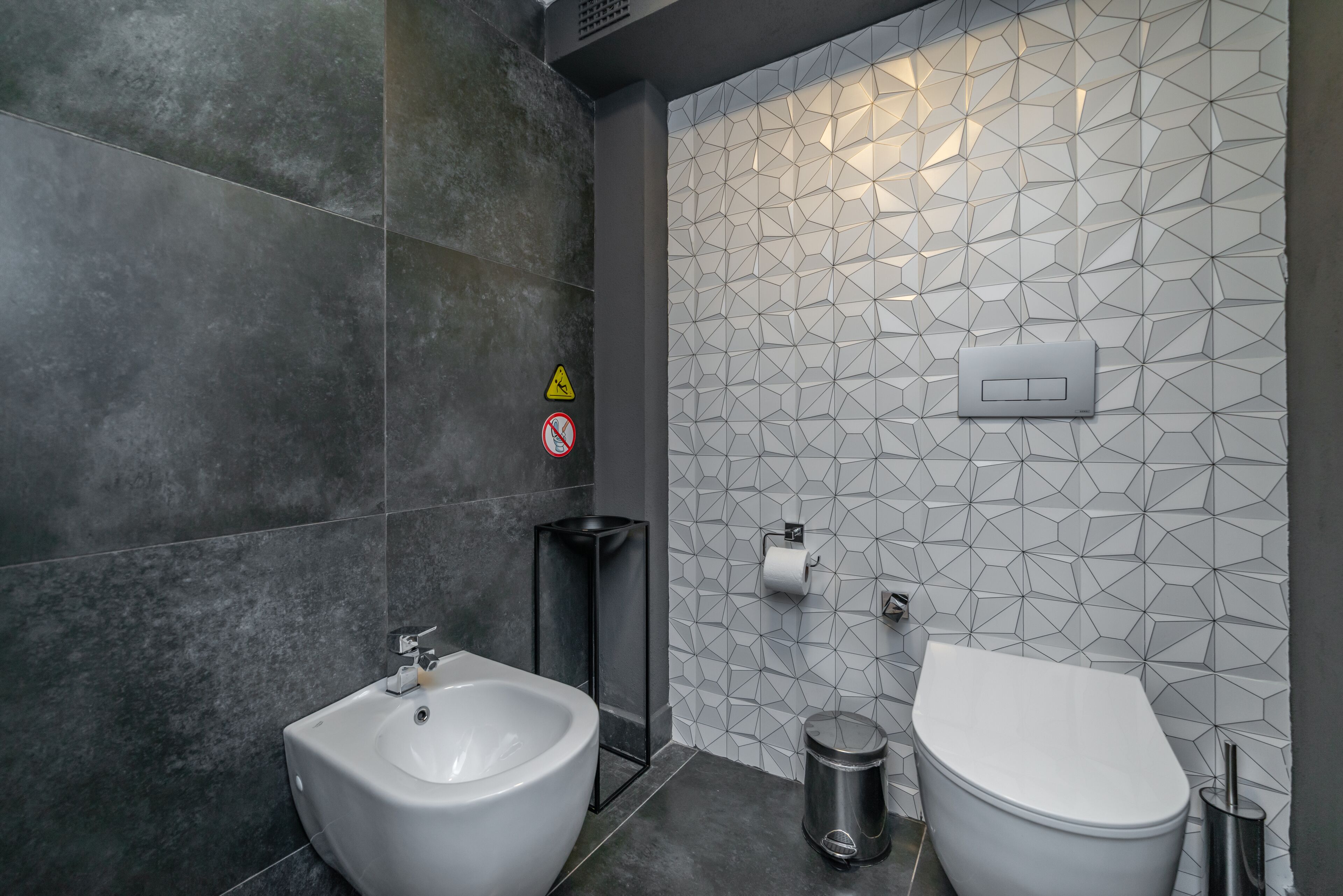 Et moderne badeværelse med bidét, toilet og skraldespand.