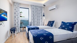 A hotel room with two beds, a TV, a balcony with a view of the sea, and an air conditioning unit. - Ece Marina Suites (Fethiye)