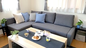 Una sala moderna con un sofá seccional gris, una mesa de centro de madera y dos plantas en macetas.