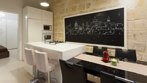 Eine moderne Küche mit einer weißen Kochinsel, Barhocker und einem großen schwarz-weiß-Kunstdruck mit Stadtansicht an der Wand.
