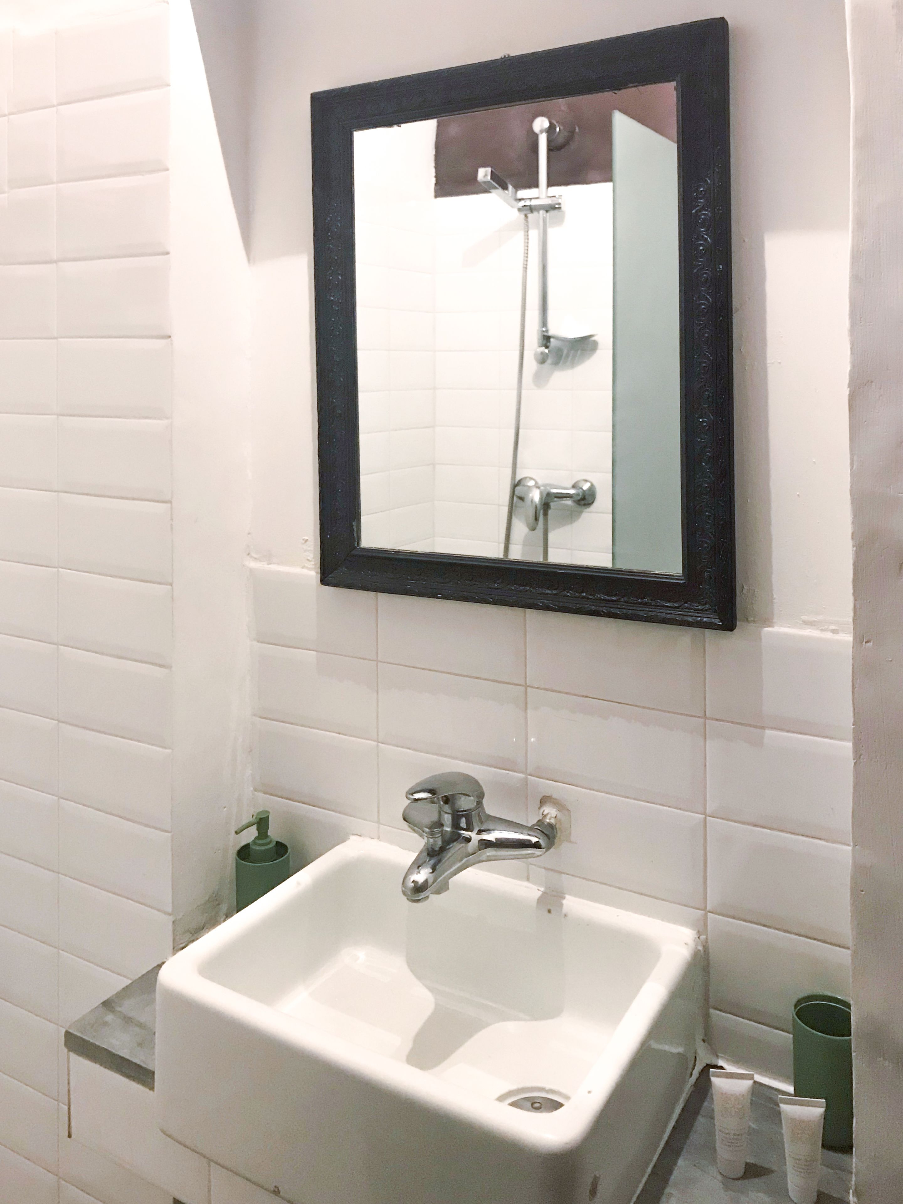 A bathroom with a white sink, a mirror, and a shower.