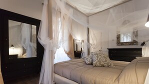 Ein Schlafzimmer mit einem Bett, einem großen Spiegel, einer Kommode und einem Nachttisch mit einer Lampe.