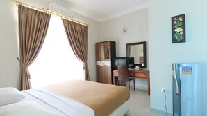 A hotel room with a bed, a desk, a chair, a television, and a refrigerator. - Ge JacMart Homestay (Makassar)