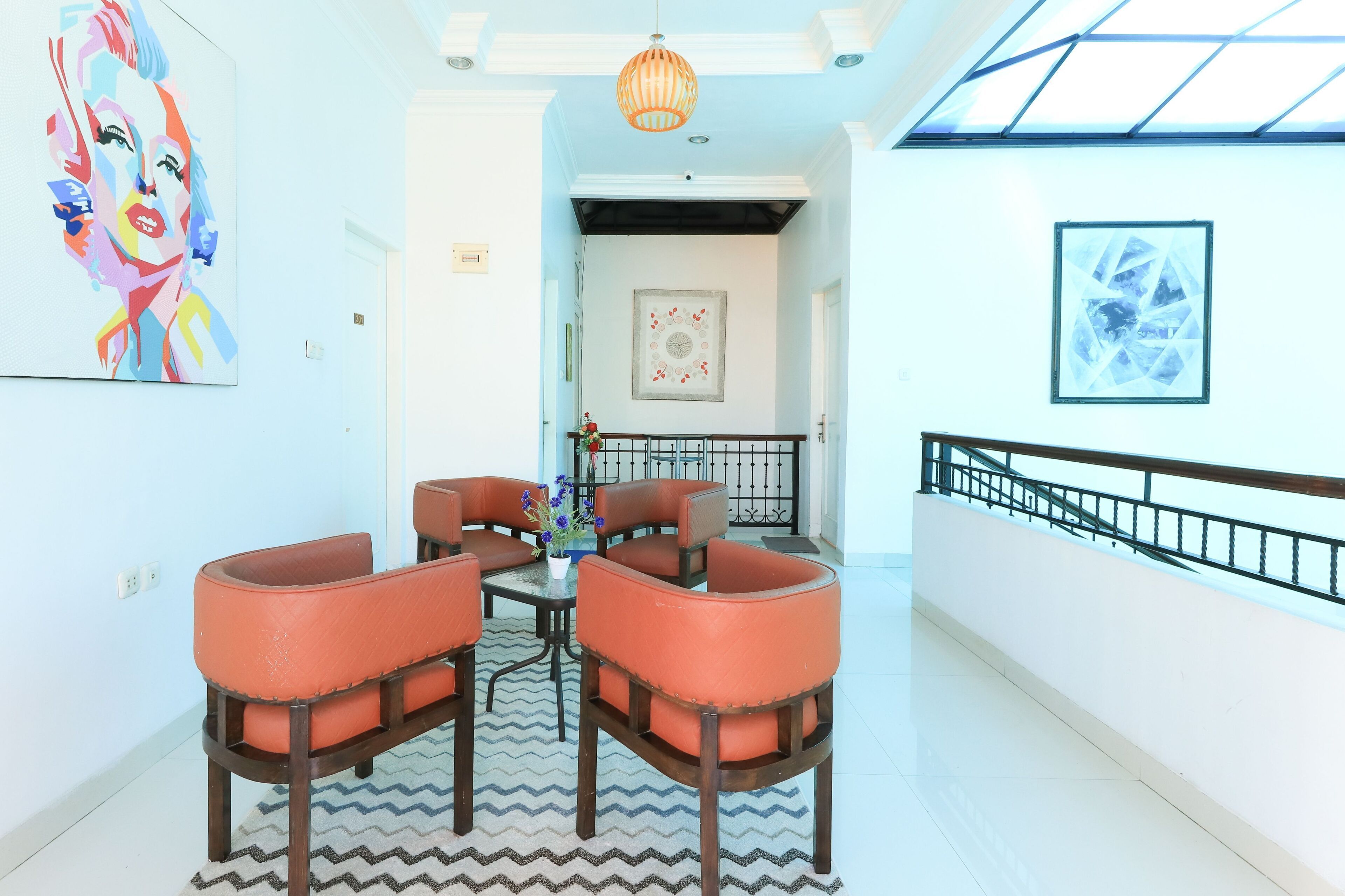 A modern interior with a dining area featuring orange chairs, a patterned rug, and a ceiling light.