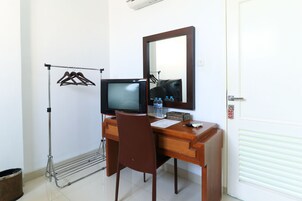 Habitación de hotel con escritorio de madera, televisión, espejo, tendedero y puerta con un número.