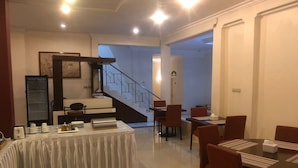 A dining area with a table set for four, a refrigerator, and a staircase leading to an upper level. - Hotel Monika (Rantepao)