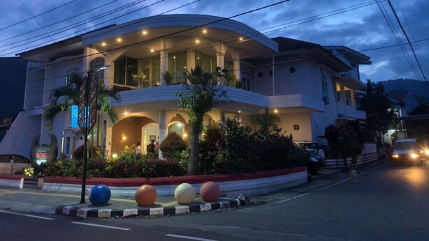 A multi-story hotel with a curved facade, multiple balconies, and a well-lit entrance. - Hotel Monika (Rantepao)