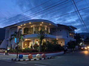 A multi-story hotel with a curved facade, multiple balconies, and a well-lit entrance. - Hotel Monika (Rantepao)