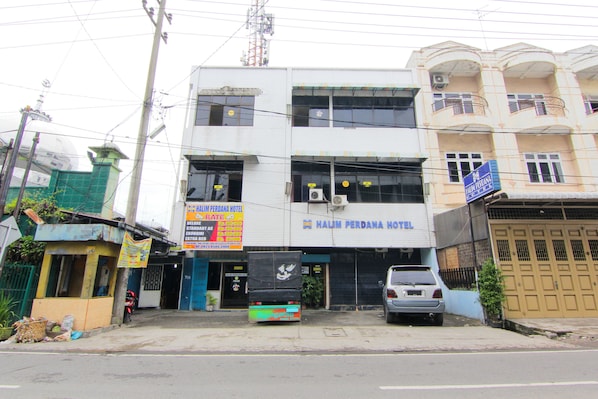 Un edificio de dos plantas con un letrero que dice 'Halim Perdana Hotel'.