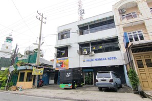 A building with a sign for 'Halim Perdana Hotel' and a parked truck and car in front. - Hotel Halim Perdana (Medan)