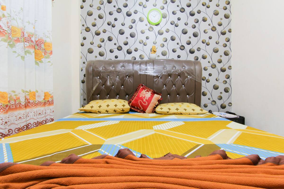 A bed with a geometric patterned bedspread, a tufted headboard, and decorative pillows.