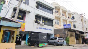 Un edificio con un cartel que indica Hotel Halim Perdana. Tiene varios pisos, balcones y un camión estacionado adelante.