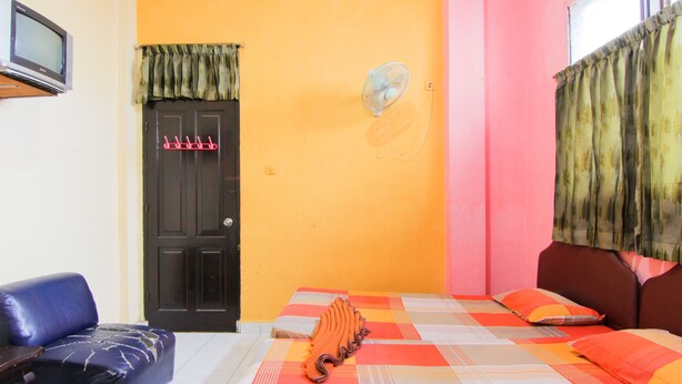A room with a bed, a chair, a television, and a door. - Hotel Halim Perdana (Medan)