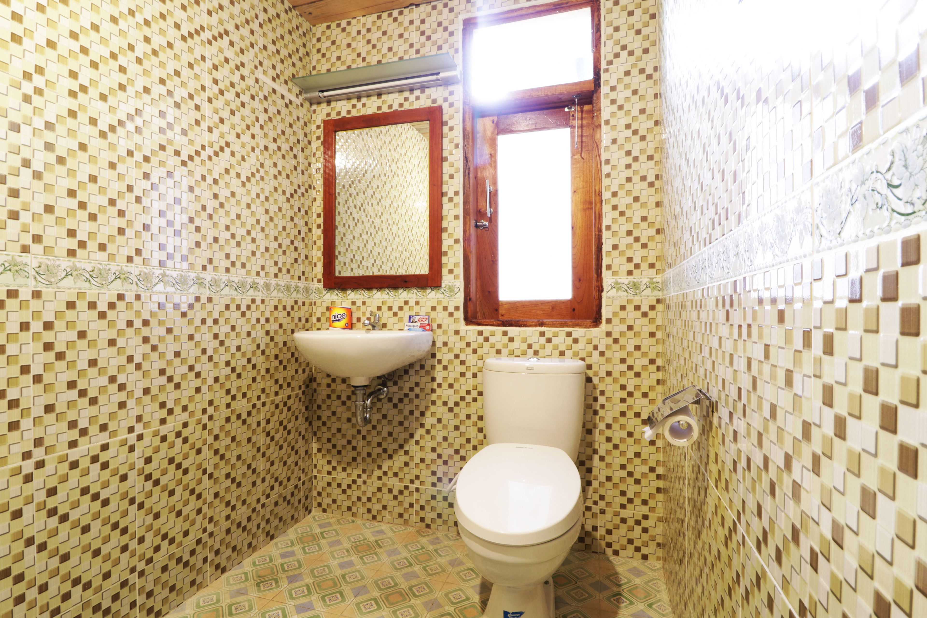 A bathroom with a tiled floor, a sink, a toilet, and a mirror.