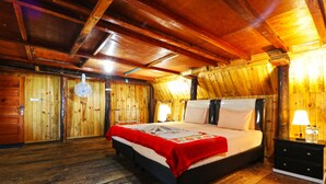 Een kamer met houten lambrisering, een bed, nachtkastjes en een plafondventilator.
