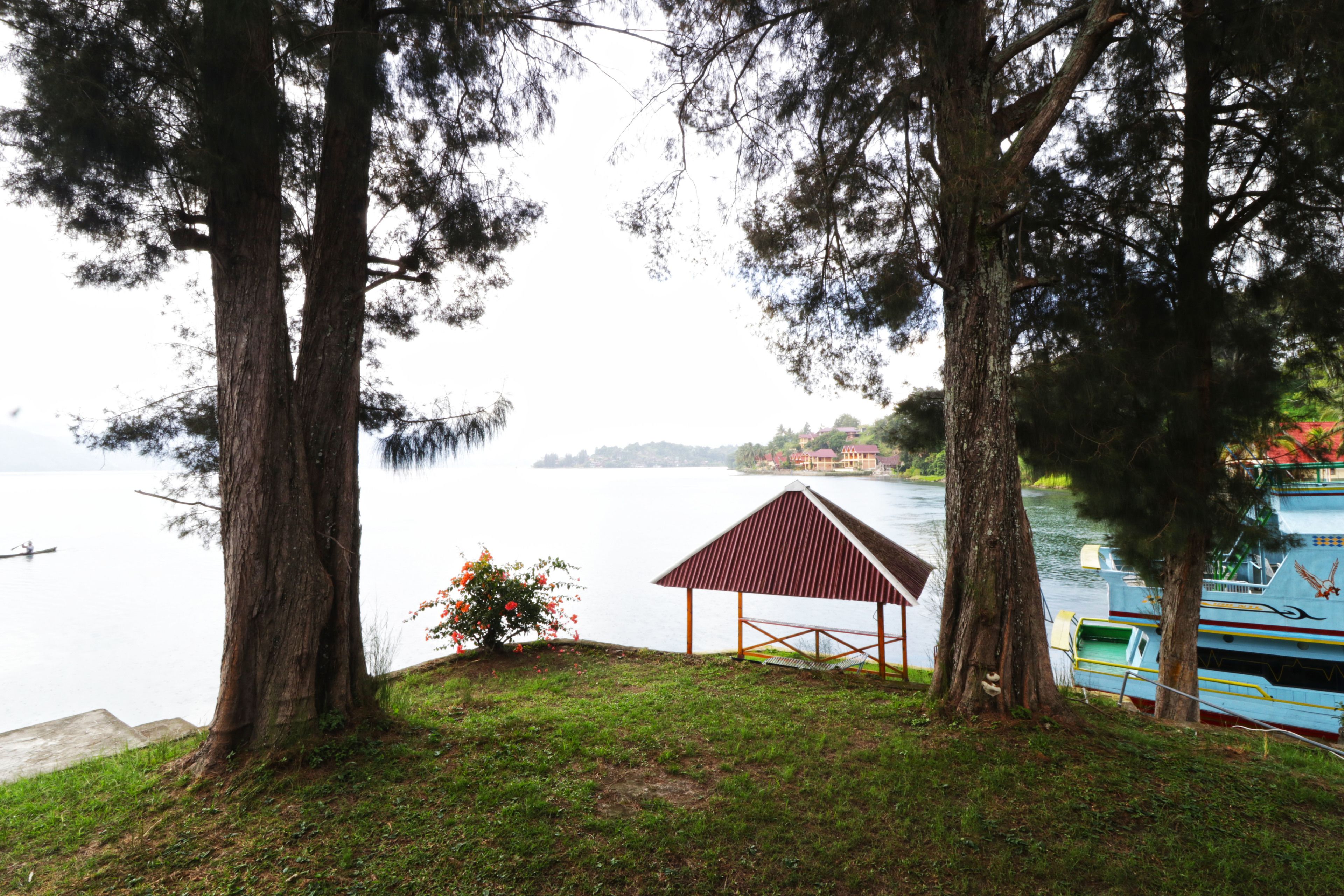 A lakeside view with a gazebo, trees, and boats.