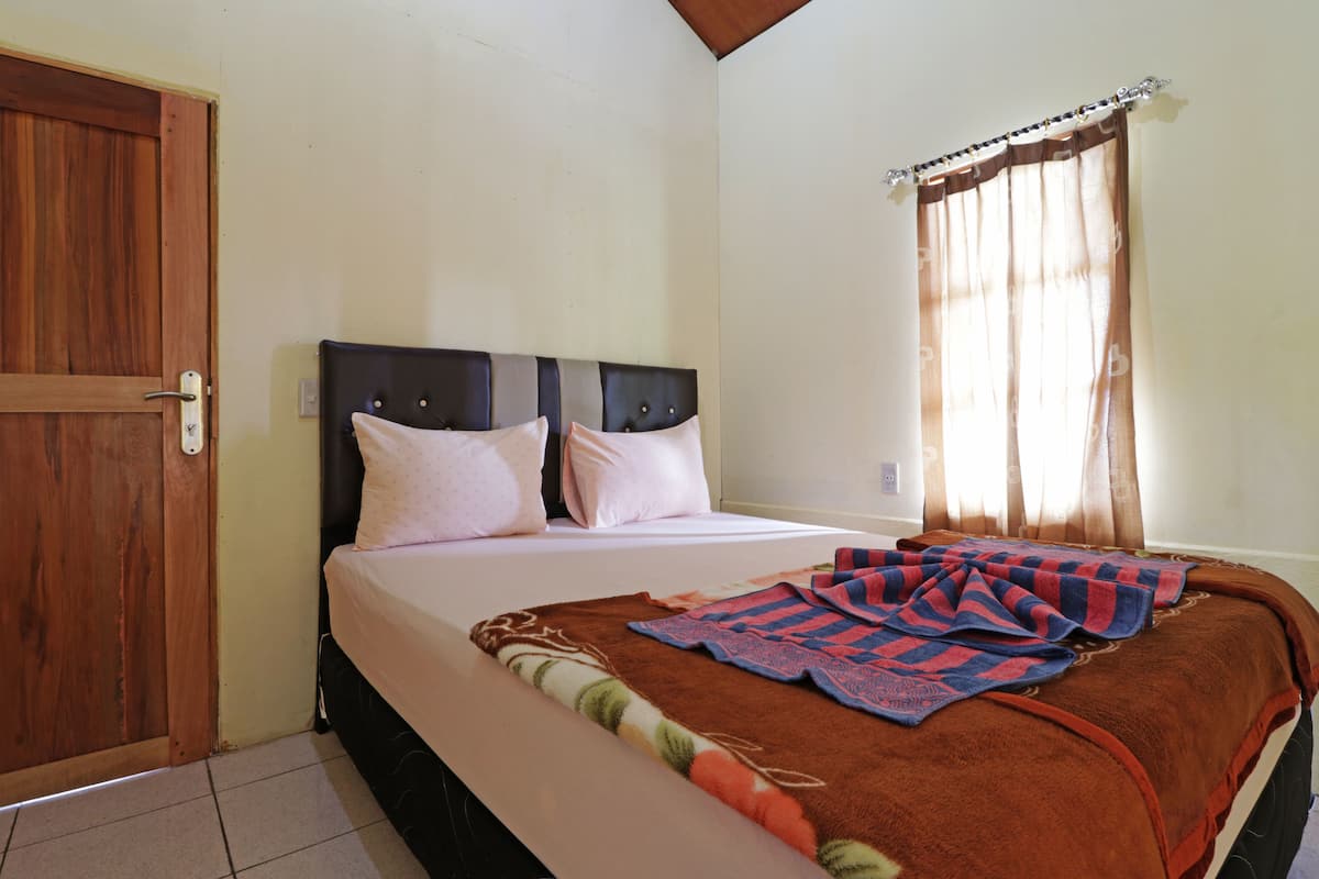 Quarto com cama, porta de madeira e janela com cortinas.