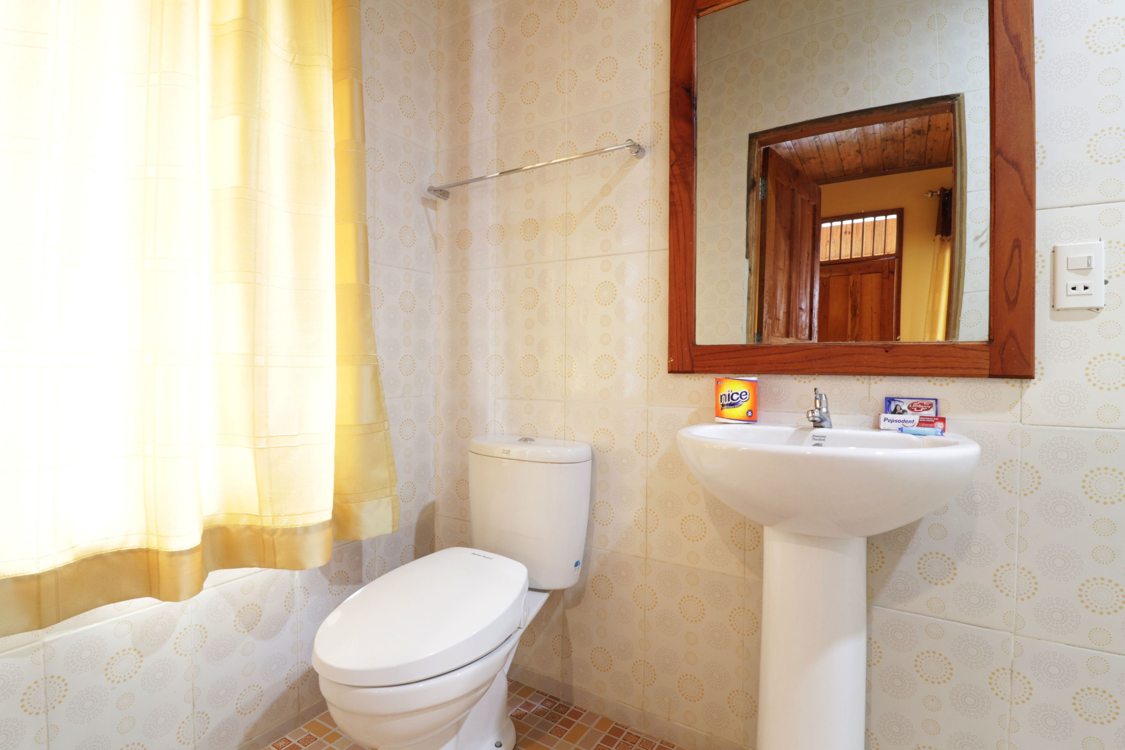 Un baño con inodoro, lavamanos y espejo.