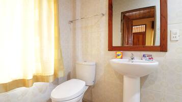 Un baño con inodoro, lavamanos y espejo.