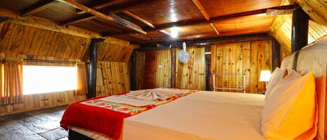 Une pièce de style cabane en bois, avec un lit, une fenêtre et un ventilateur de plafond.