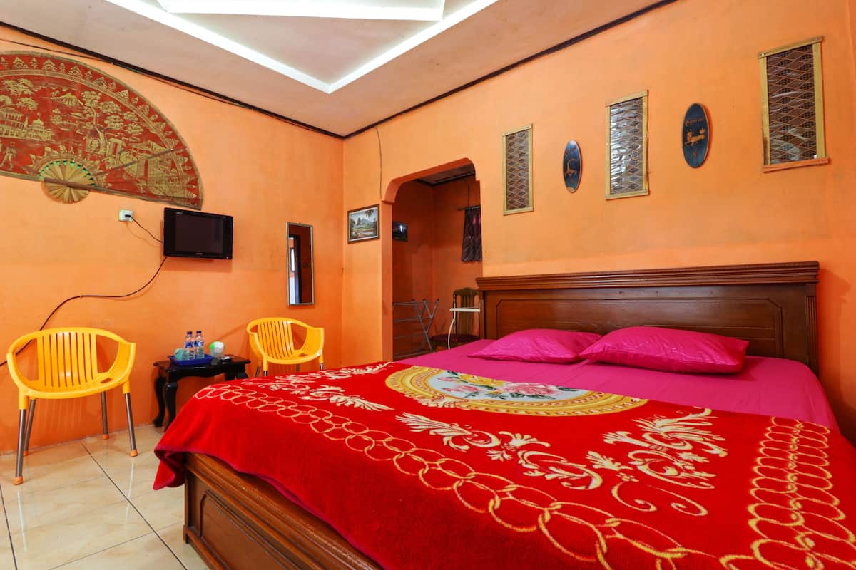 A room with a bed, two chairs, a TV, and a decorative wall piece.