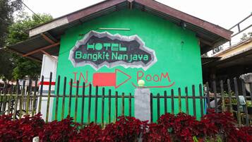 A green building with a sign that reads "HOTEL Bangkit Nan Jaya" and an arrow pointing to the right labeled "ROOM".