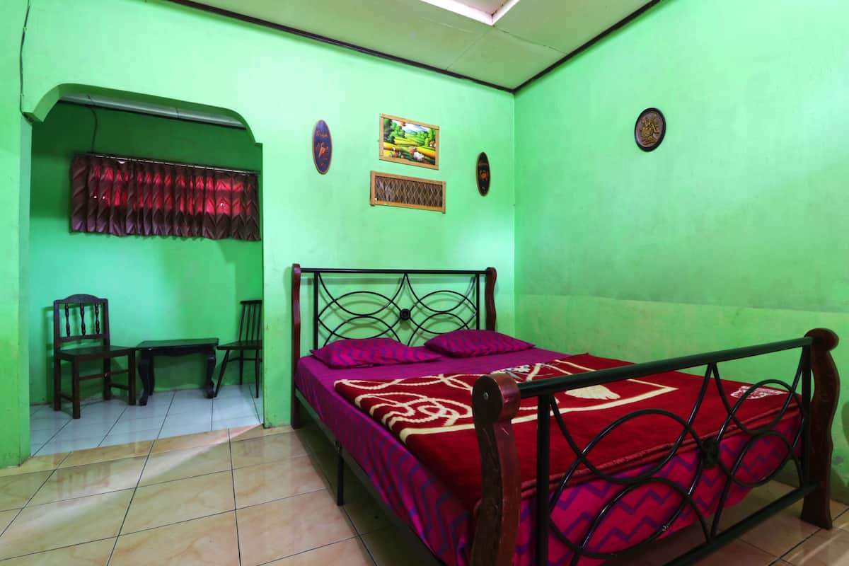 A room with a bed, two chairs, a small table, and a window with a curtain.