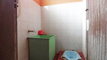 A small, basic bathroom with a green sink, a red cup, and a blue toilet.
