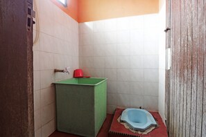 A small, basic bathroom with a green sink, a red cup, and a blue toilet.
