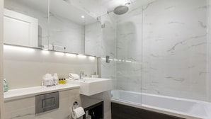 Ein modernes Badezimmer mit einer Duschkabine, einem weißen Waschbecken und einer Badewanne in Dunkeltönen.