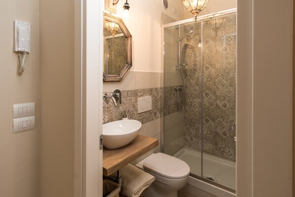 A bathroom with a white sink, a toilet, and a glass-enclosed shower.
