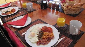Un bufé de desayuno con platos de huevos, frijoles y tocino, junto con jugo y pan.