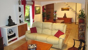 Una sala de estar con sofá, mesa de centro y una escalera que sube a un nivel superior.