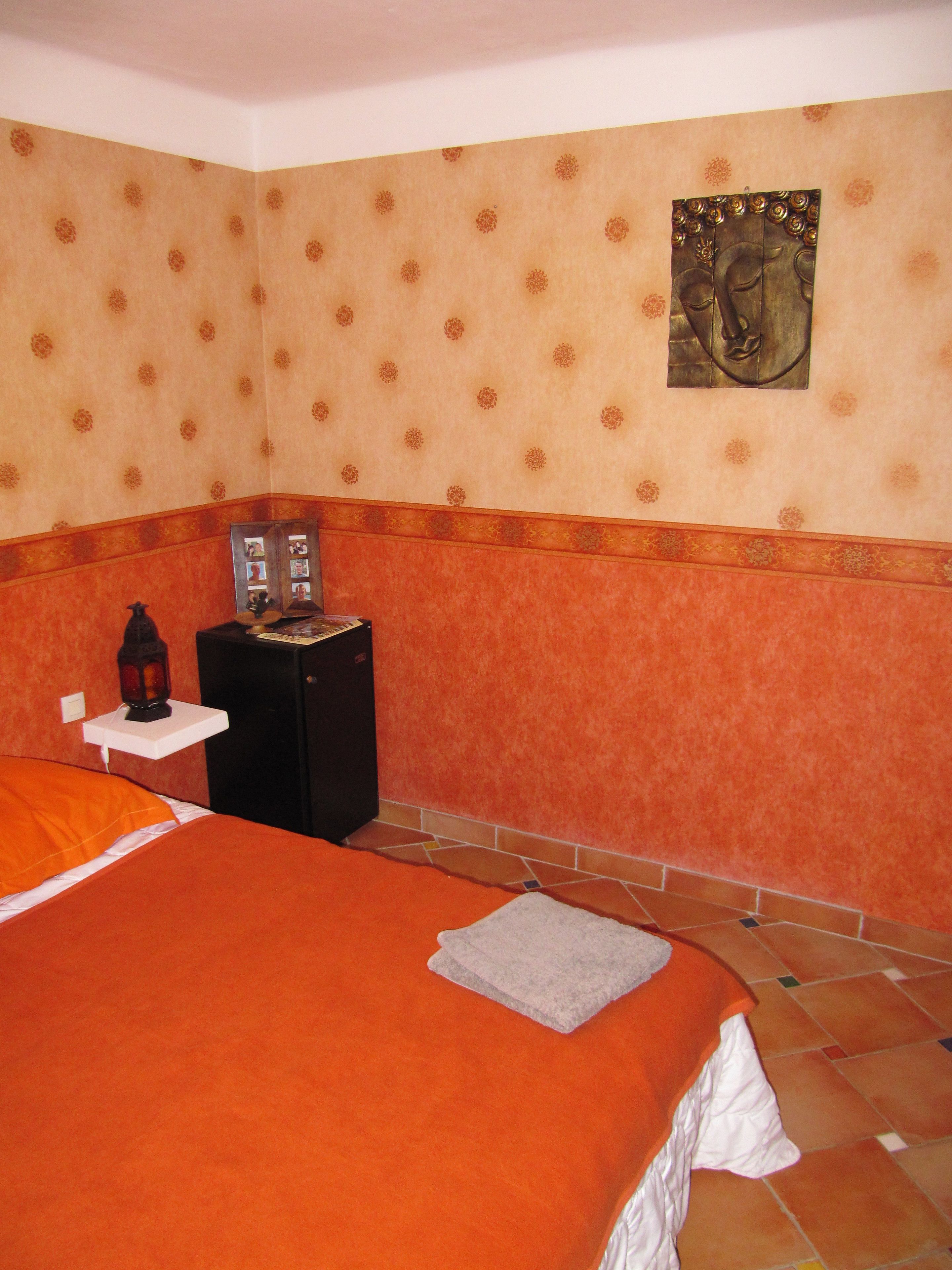 Hotelkamer met een groot bed, nachtkastje, lamp en een klein tafeltje met een fotolijst.